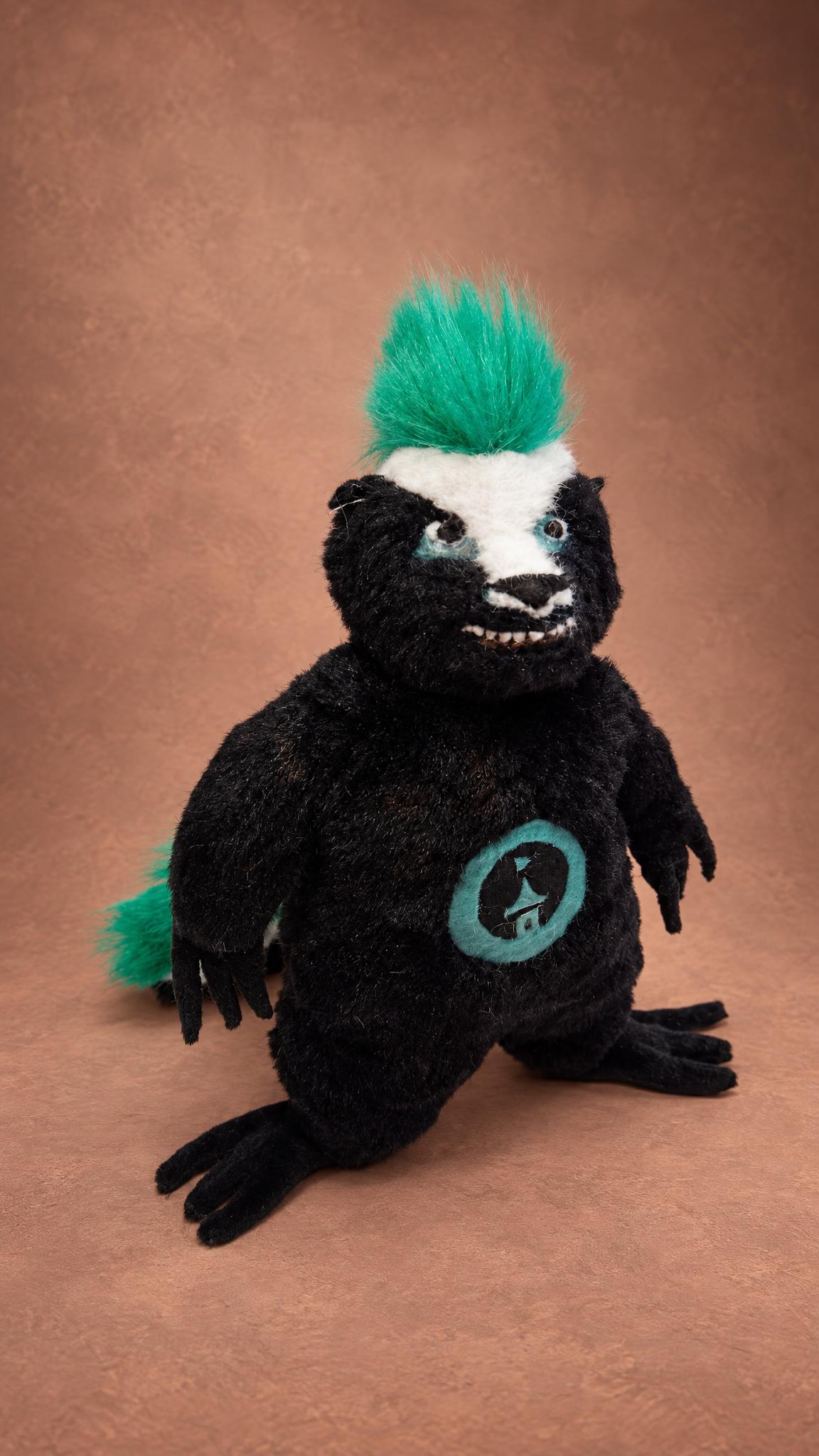 Punk honey badger plush in black faux fur with a teal mohawk and toothy grin, a custom mascot made to order