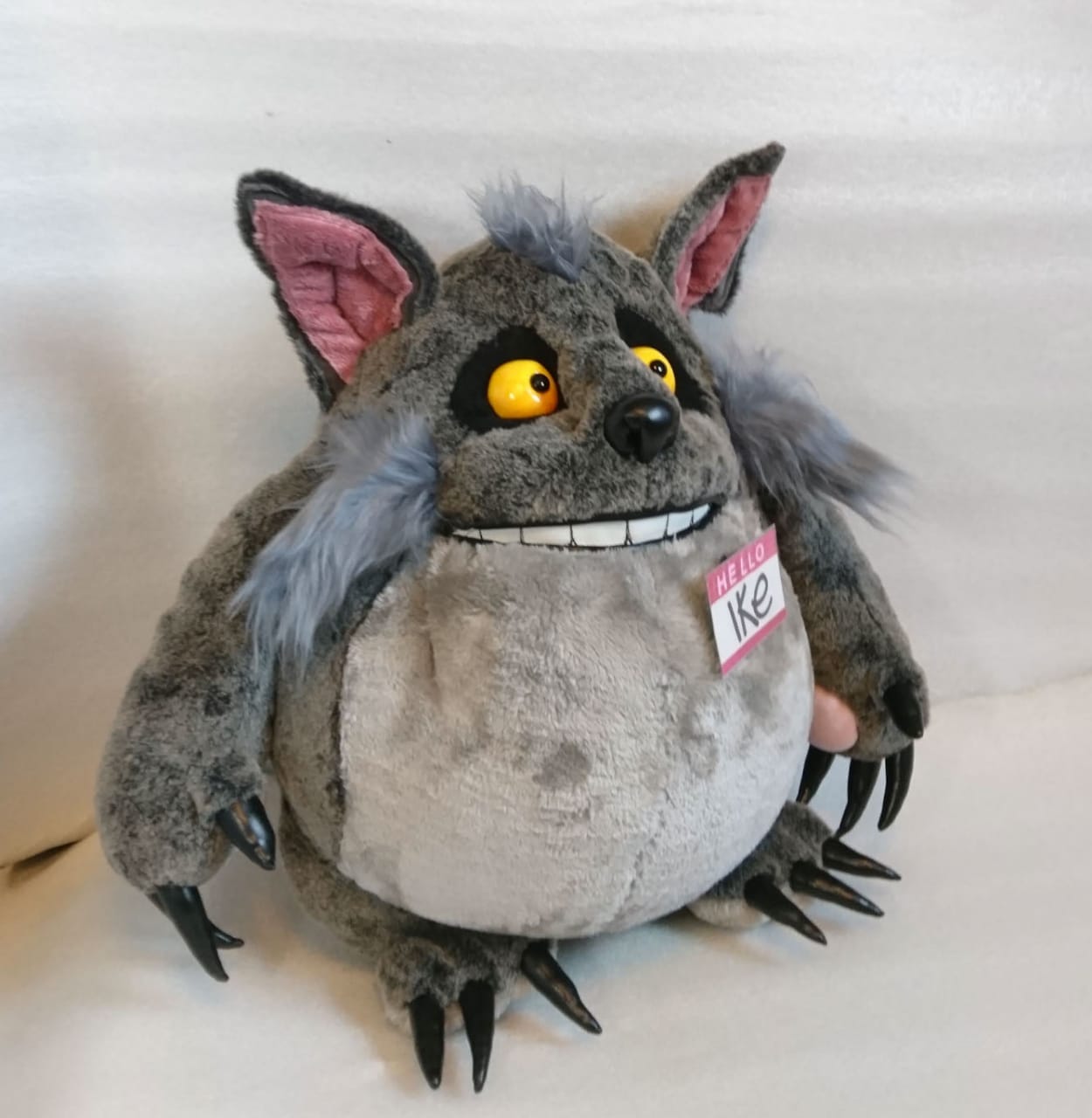 Ike wolf plush with a HELLO name badge Ike wolf plush with a HELLO name badge on a pale grey belly, yellow eyes and blue-grey cheek tufts, sewn by hand
