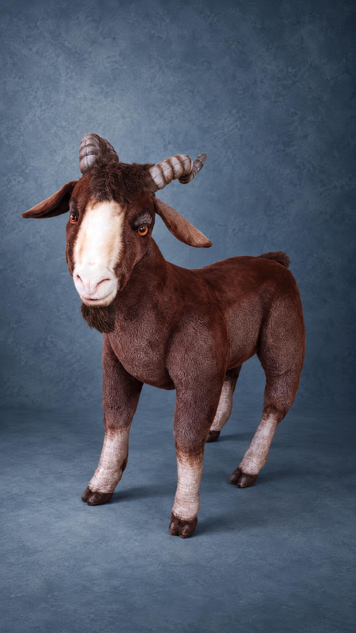 Big brown goat plush with a white face blaze, amber eyes and ridged horns, sewn by hand to order
