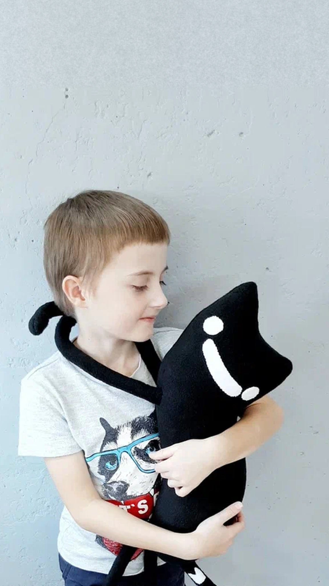 Long-legged black cat plush from a drawing, its tail around a boy's shoulders, sewn to order by hand