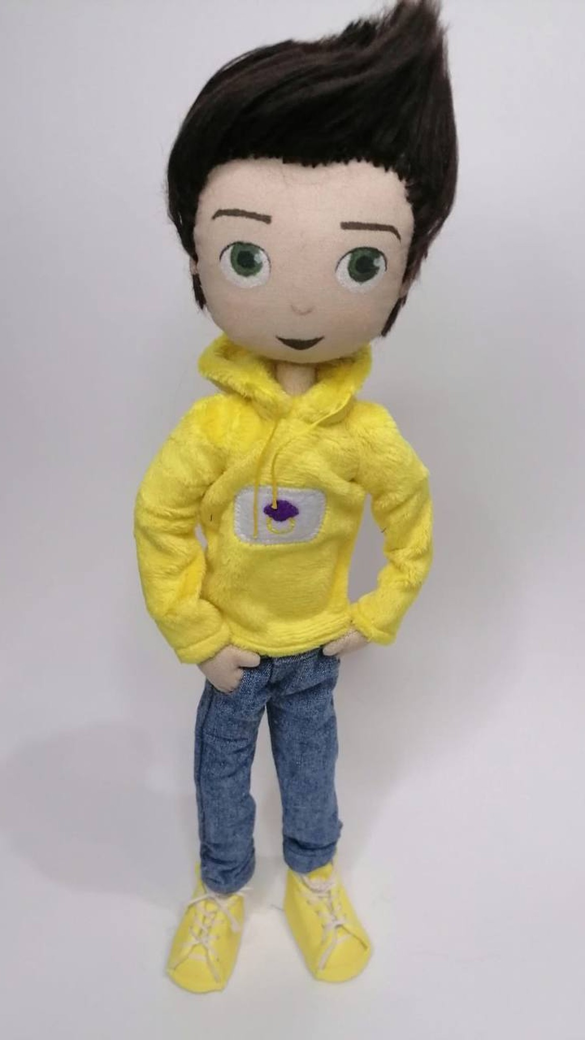 Custom mascot doll in a yellow plush hoodie and denim jeans, hands at his hips, made to order