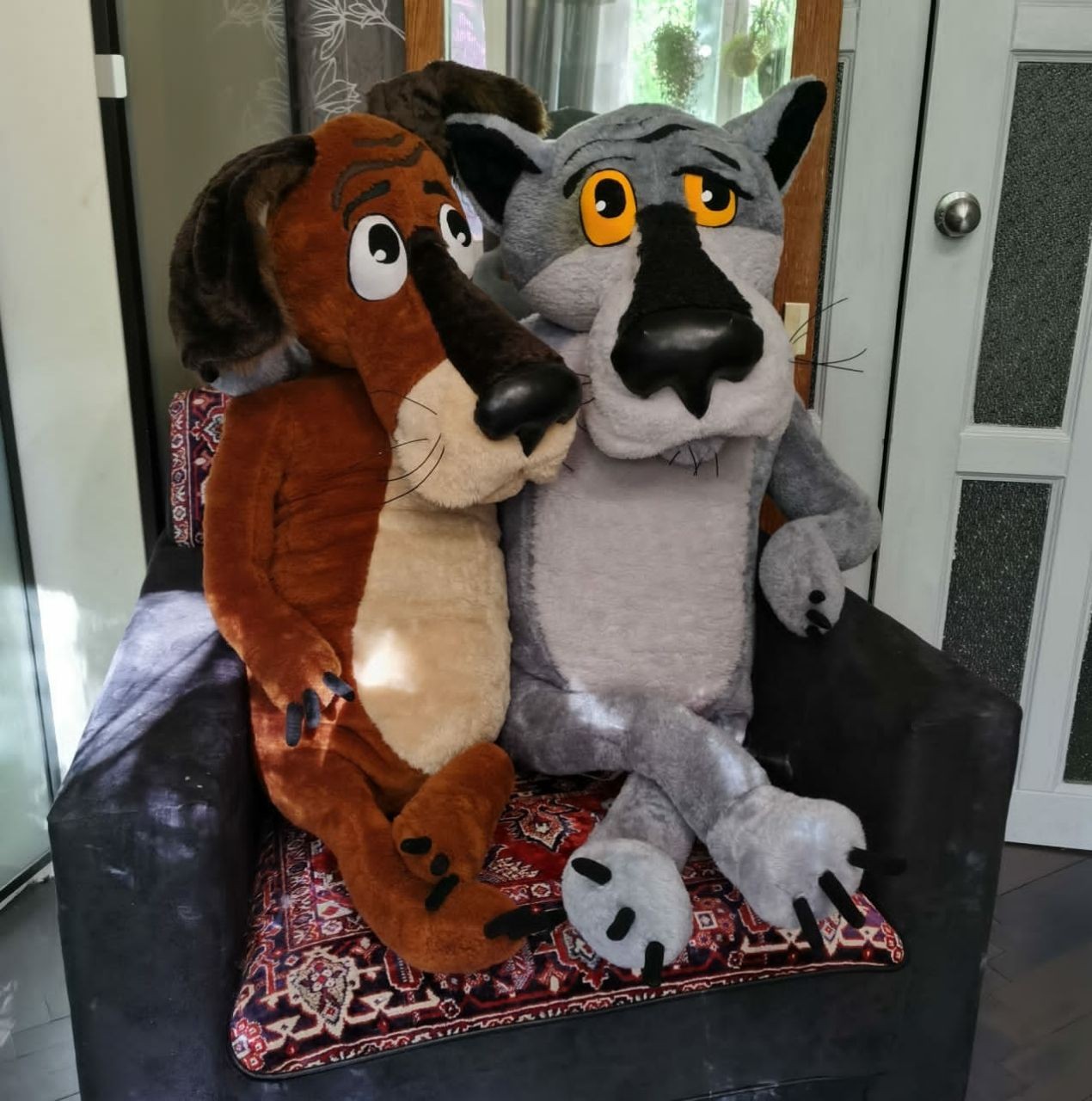 Once Upon a Dog plush pair on an armchair Custom Once Upon a Dog plush: faux fur Dog and Wolf with long crossed legs on a rug-covered armchair