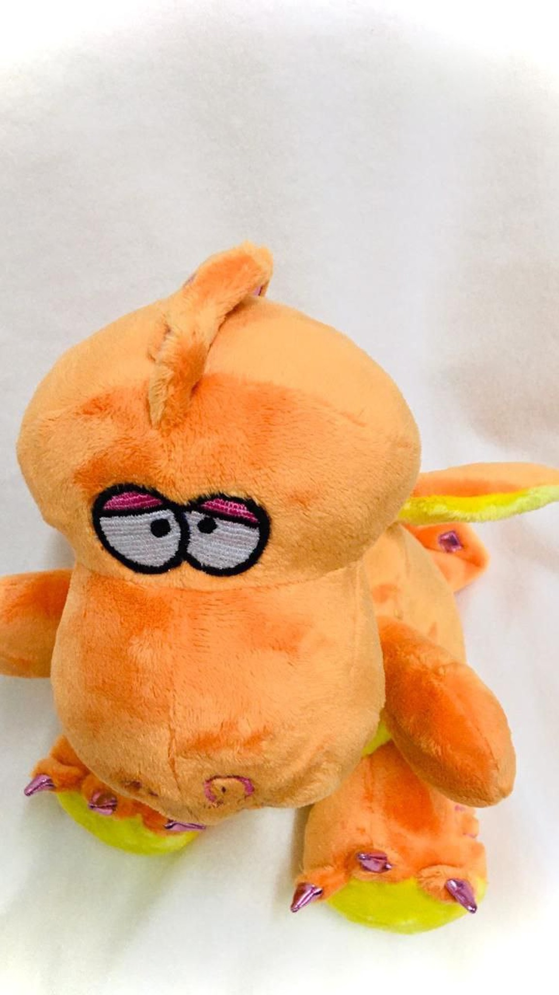 Orange dragon plush with embroidered sleepy eyes, a small horn and lime feet, sewn by hand to copy a lost toy