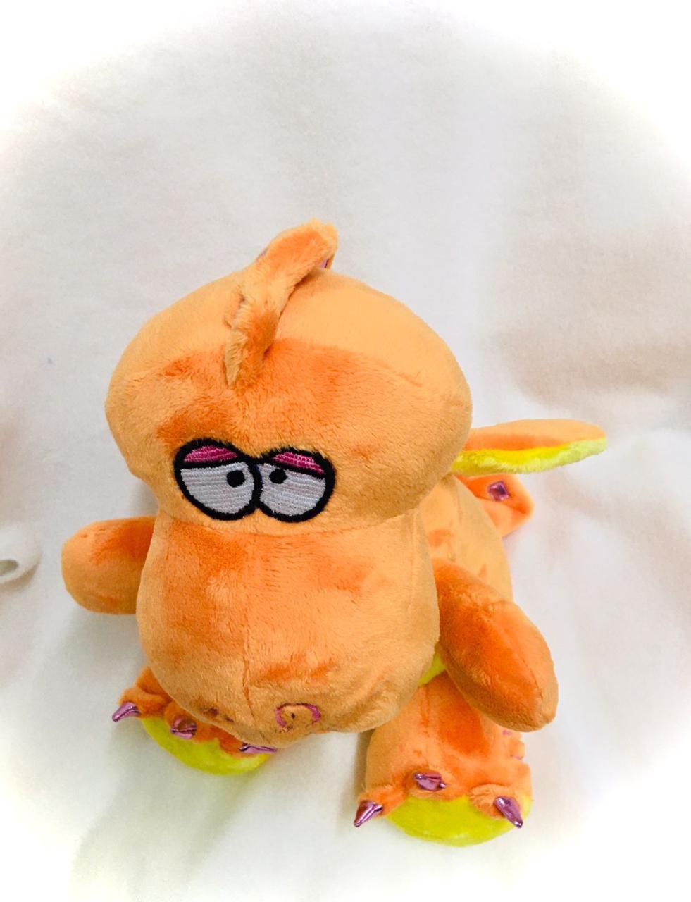 Orange dragon plush face with embroidered eyes Orange dragon plush with embroidered sleepy eyes, a small horn and lime feet, sewn by hand to copy a lost toy