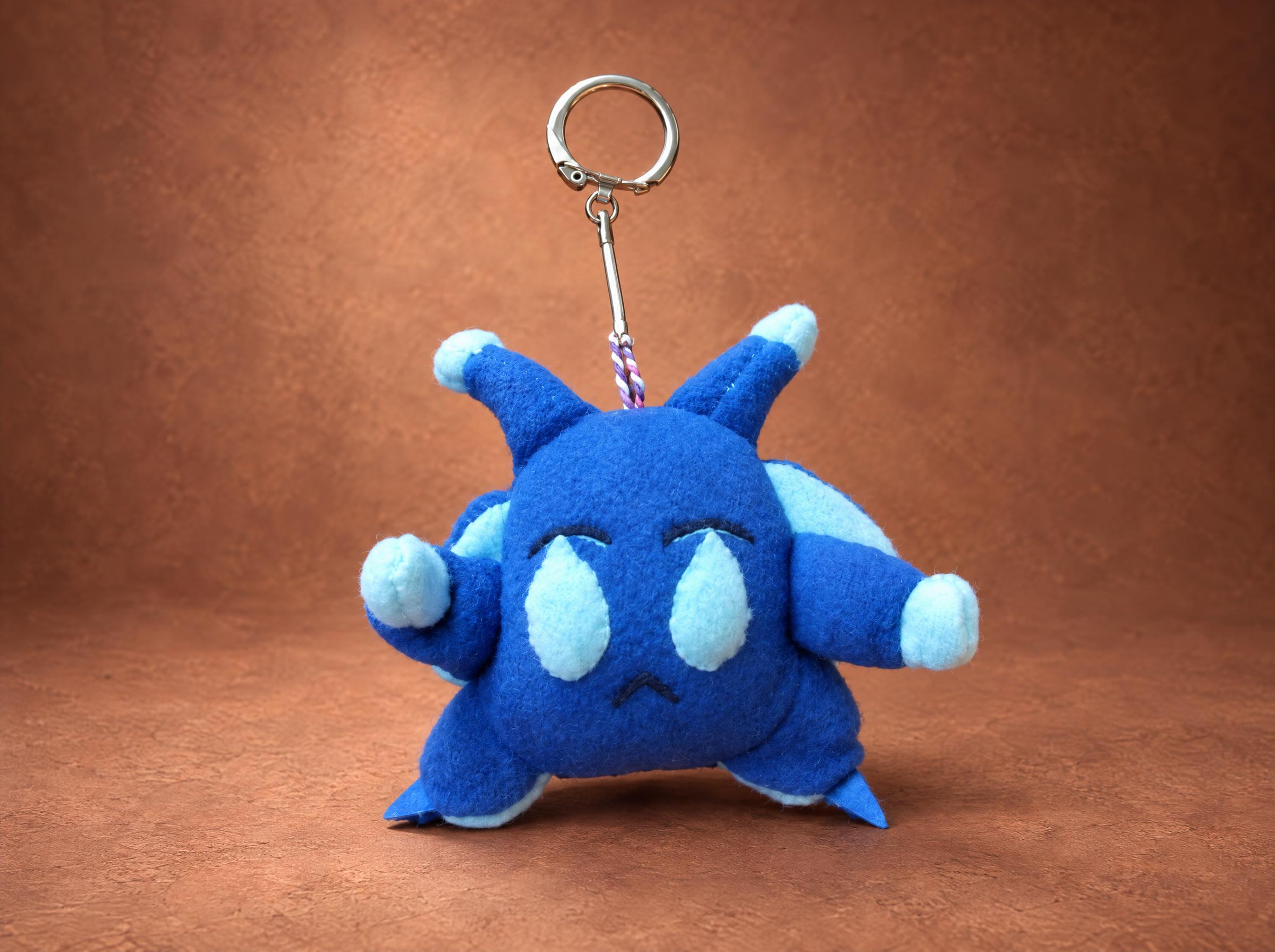 Blue Orik custom keychain plushie with pale-blue teardrop eyes, handmade to order from a clay figure
