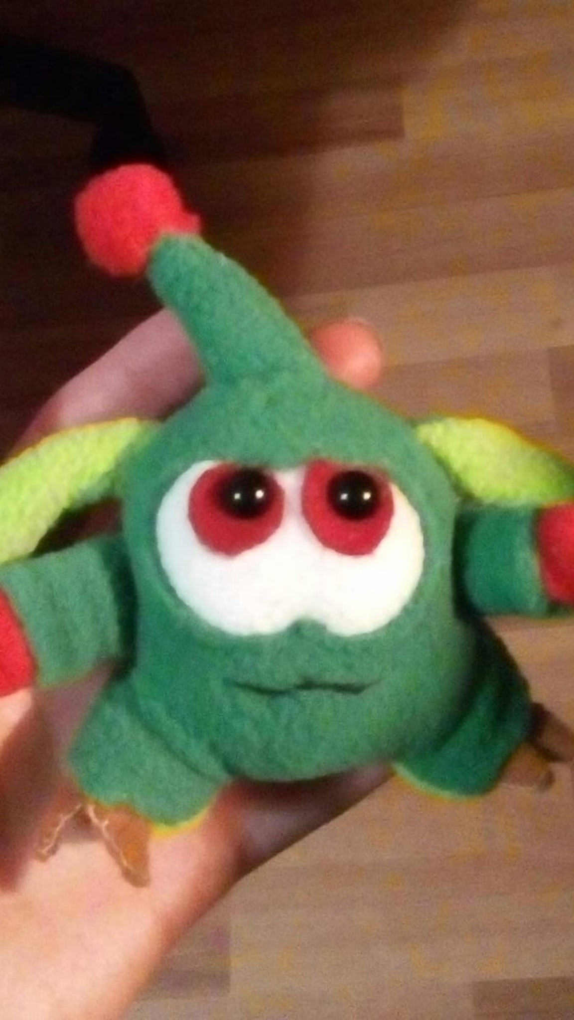 Green Orik custom keychain plush with big red eyes and a red pom-pom, handmade to order for one customer