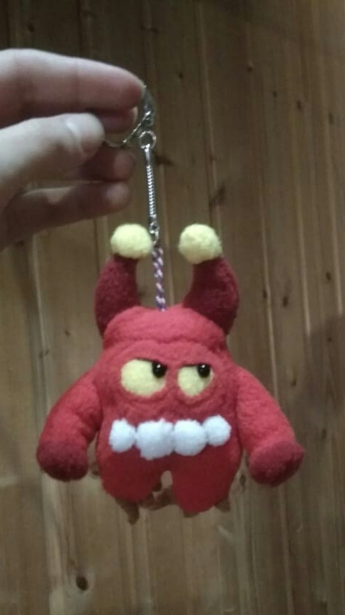 Red Orik plush keychain with horns, yellow eyes and white teeth, a custom toy sewn by hand from clay