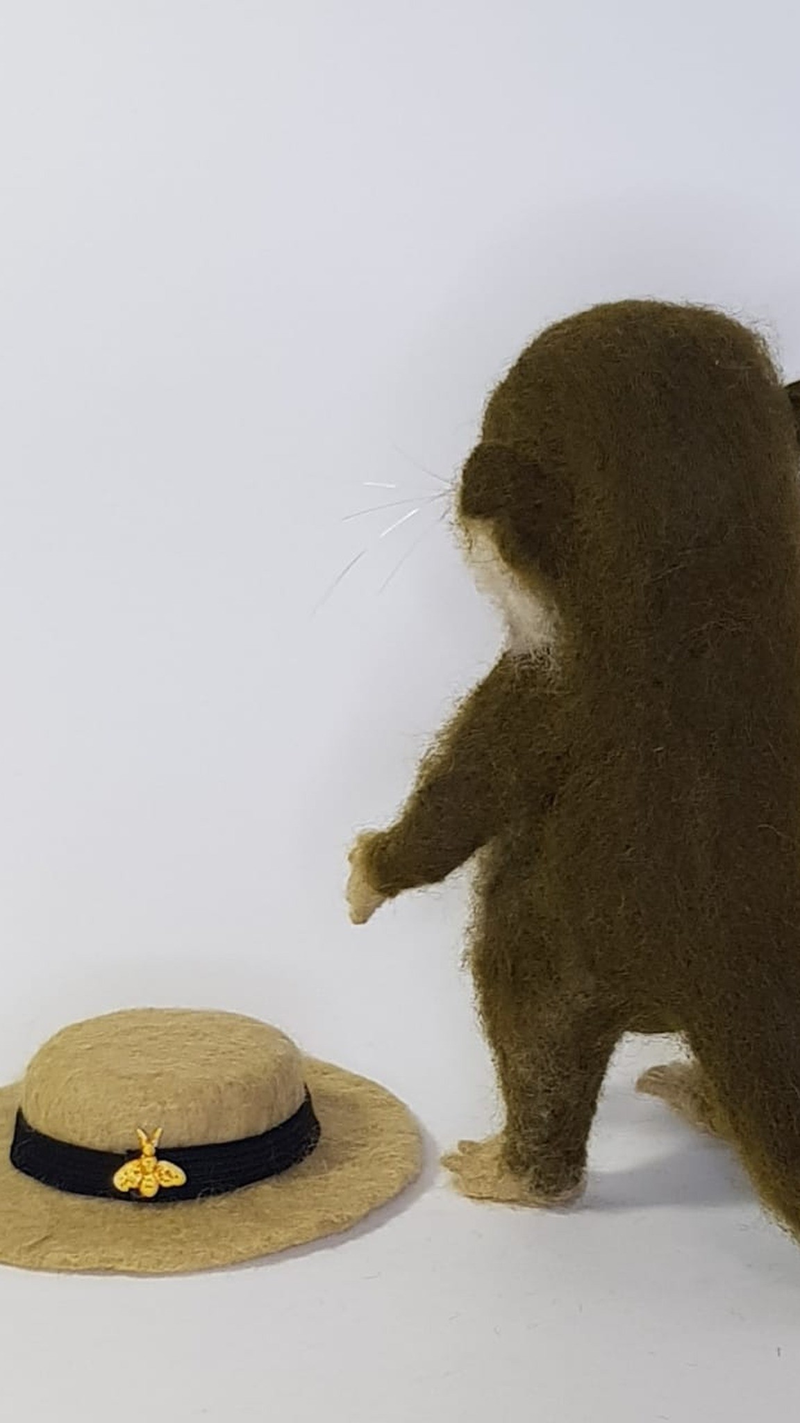Removable felted boater with a gold bee lying beside the otter plush it was made for, custom toy