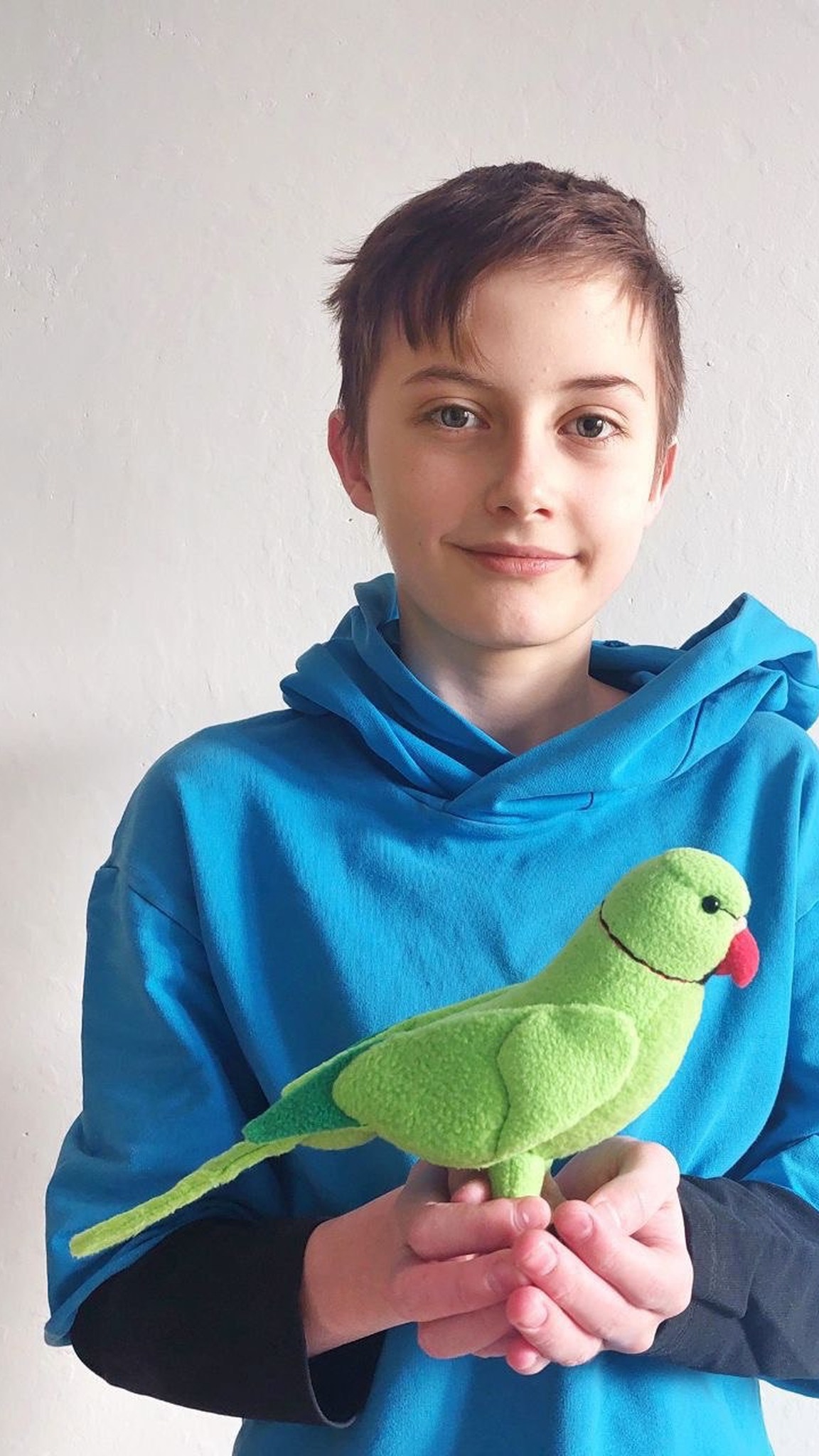 Girl holding the custom ringneck parrot plush sewn to order from photos of her pet bird