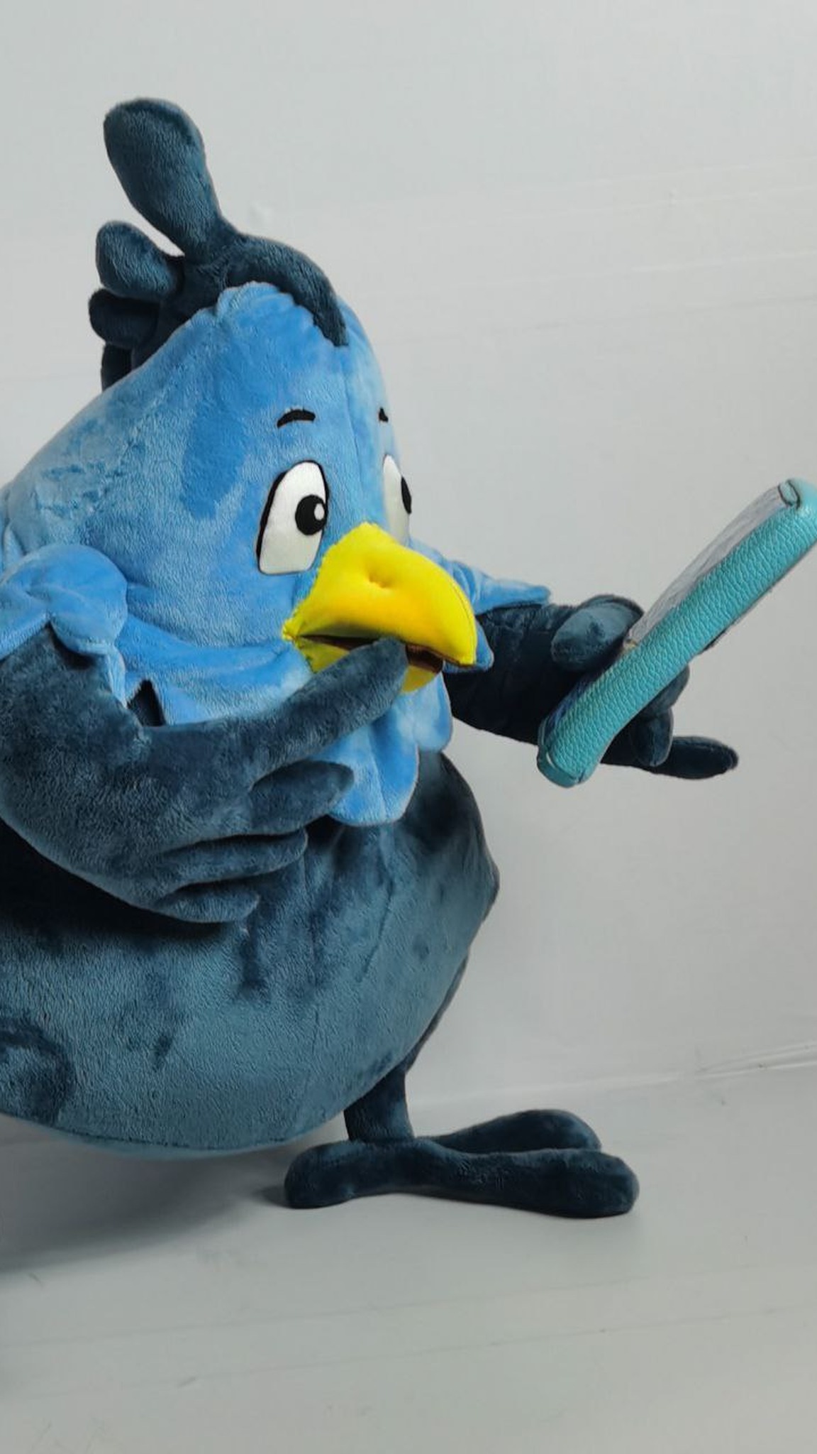 Phoenix mascot plush reading on its phone, a custom bird plush with a scalloped blue collar, sewn to order
