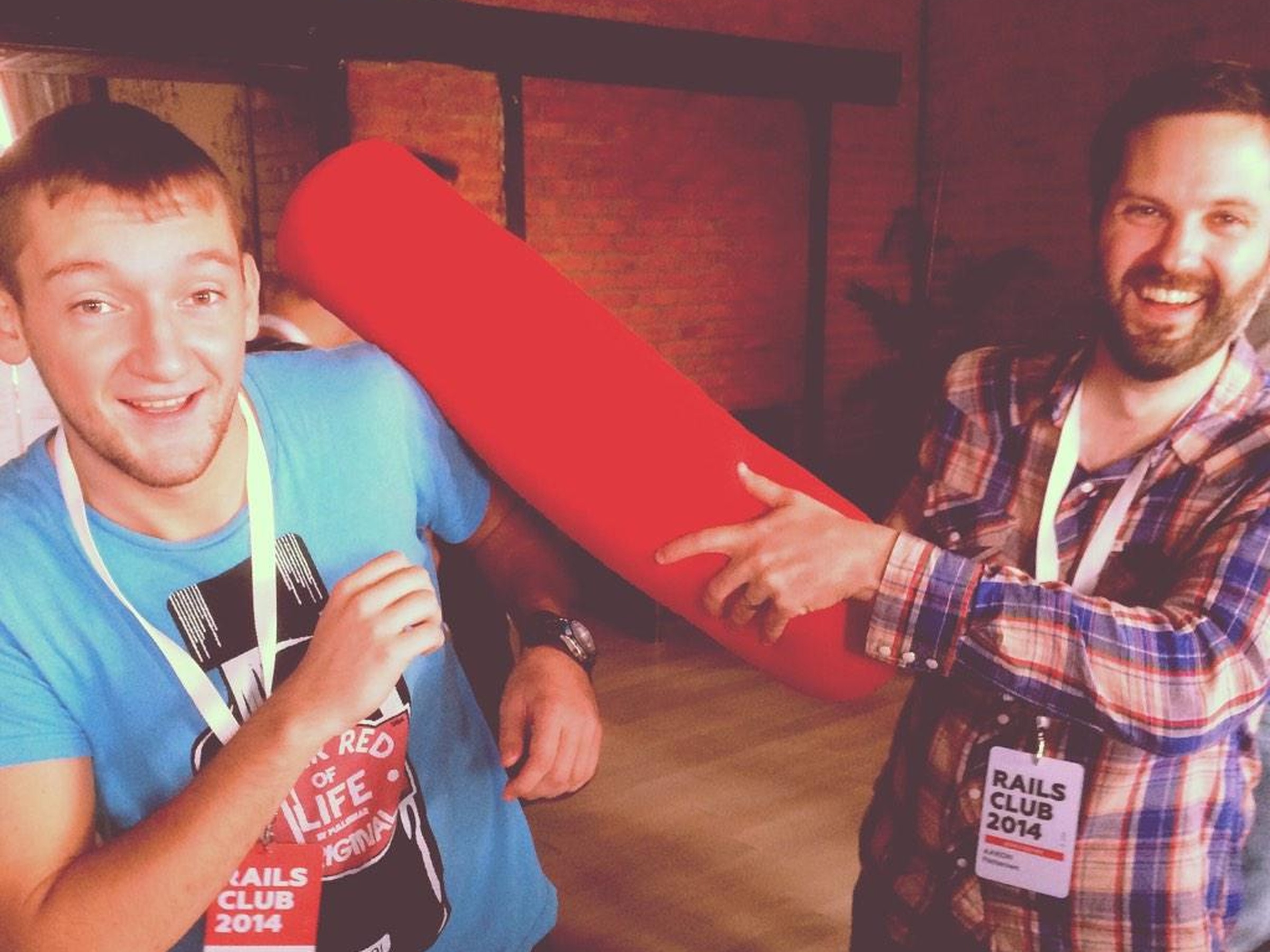 Custom pillow fight stick in soft red fabric, made to order for a company party, two smiling guests