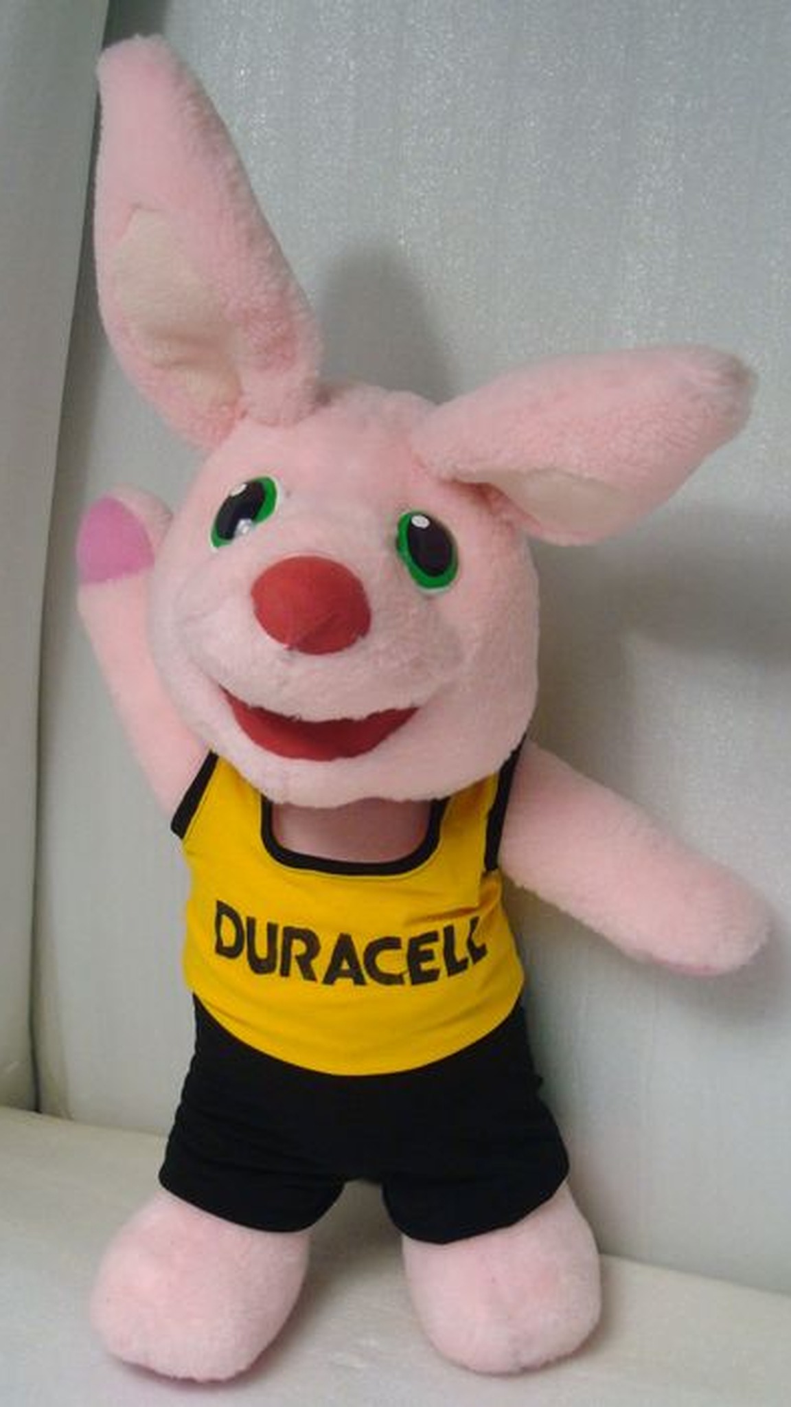 Pink bunny mascot plush waving, with a red nose and a yellow athletic top, custom made by hand to order