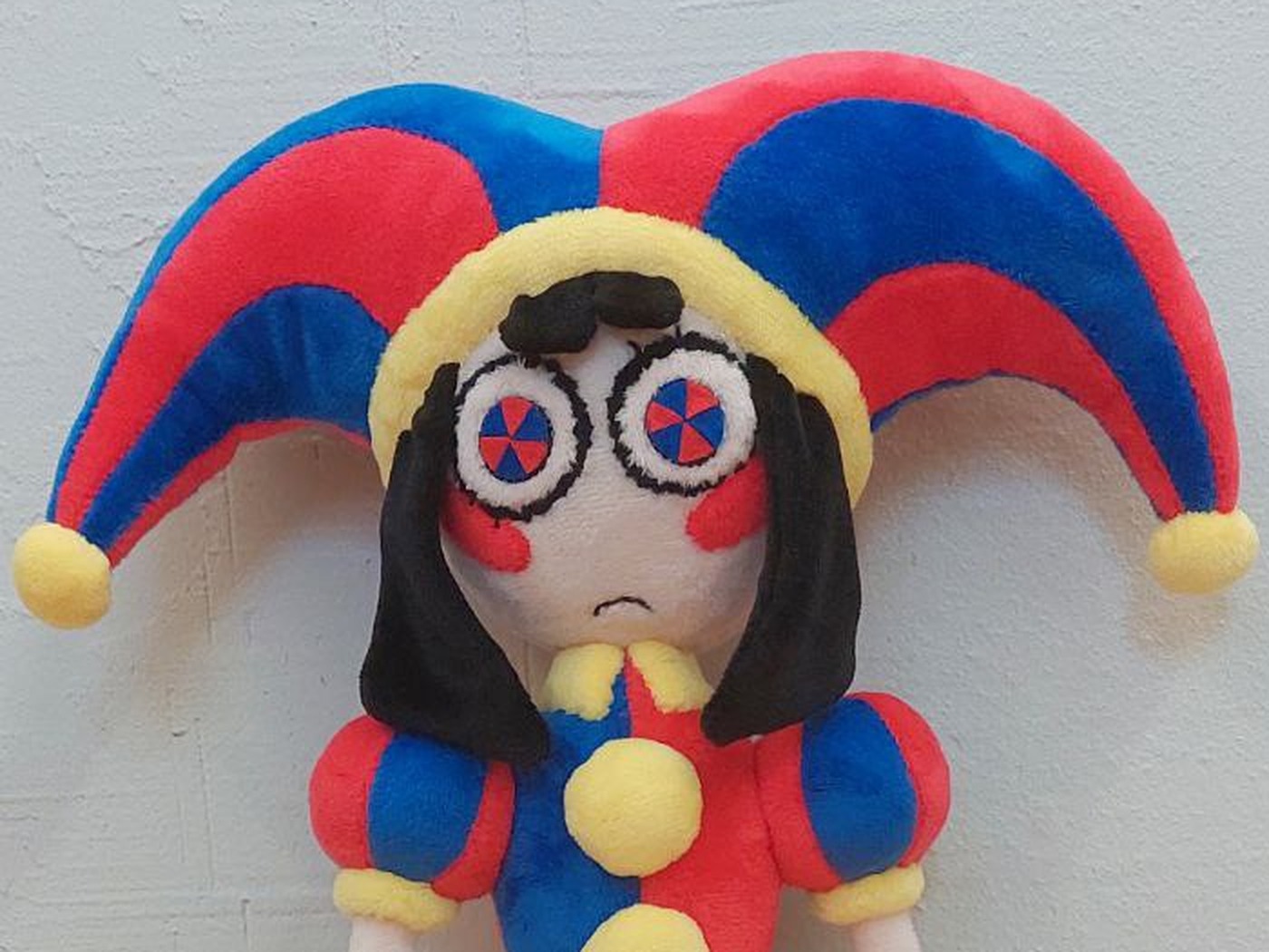 Pomni plush face and jester hat Pomni plush (TADC) with felt pinwheel eyes, red cheeks and a red and blue jester hat, handmade to order