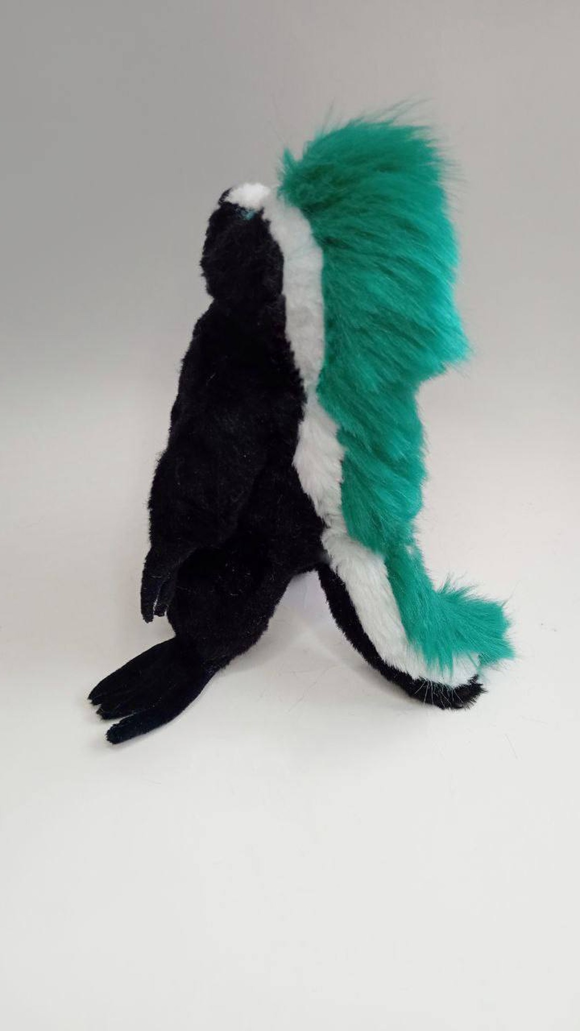 Punk honey badger plush with a white stripe and teal mohawk down to a fluffy tail, custom made to order