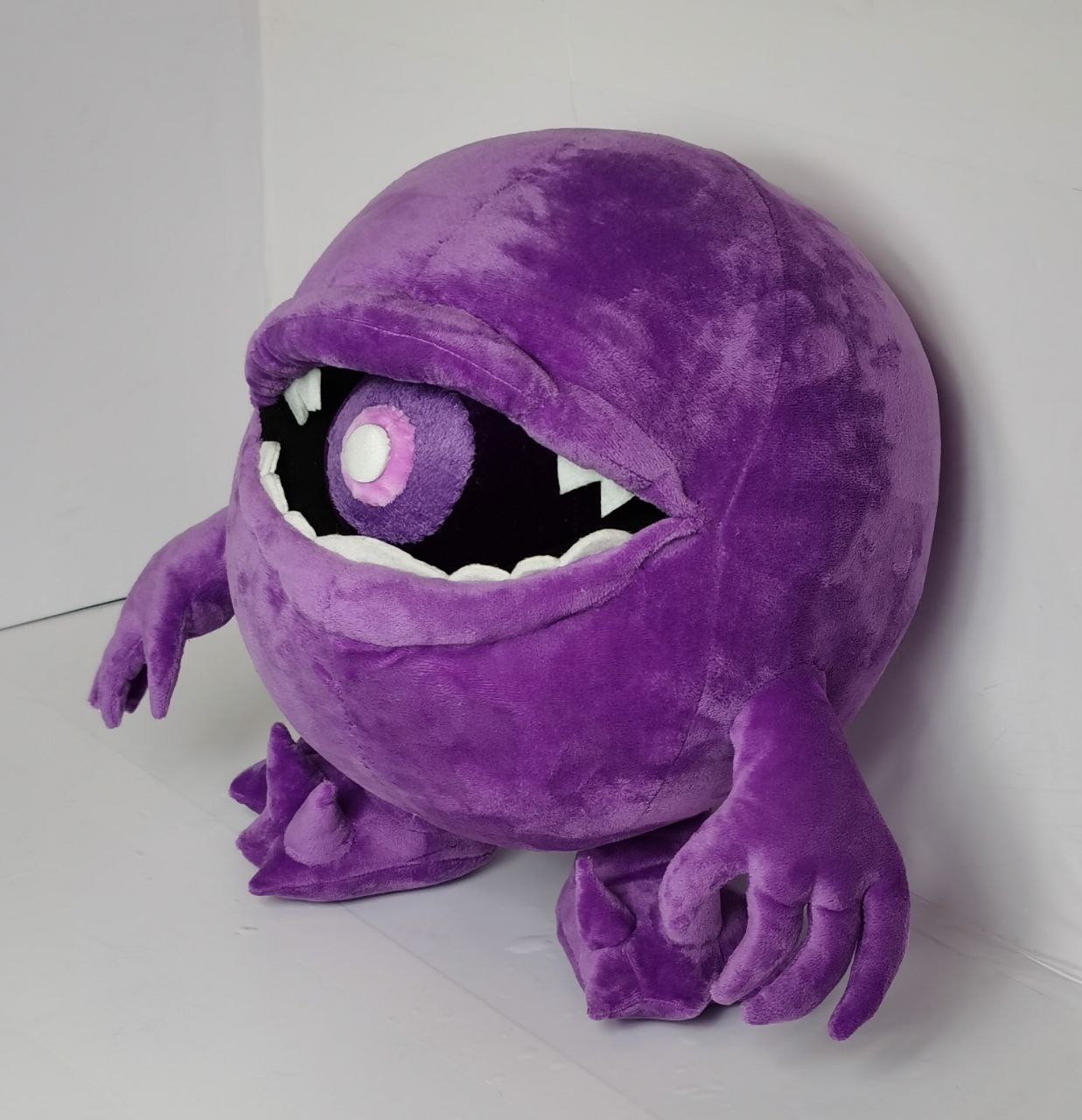 Purple monster plush with its egg Round purple monster plush with a pink-and-white ball in its mouth, sewn to order from a child's monster drawing