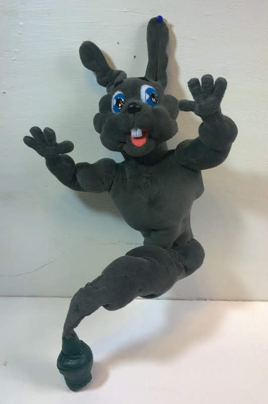 Grey rabbit genie plush in a green bottle Grey rabbit genie plush with blue eyes, buck teeth and muscular arms, tail ending in a green bottle, custom made