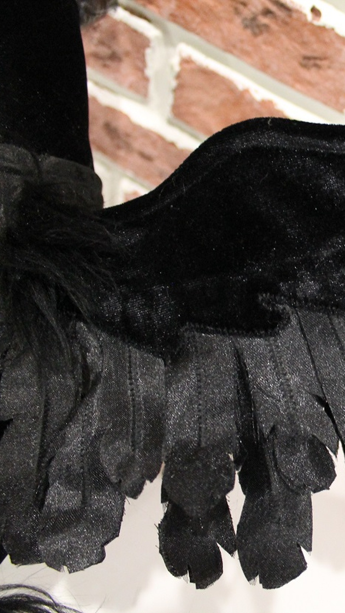 Layered glossy fabric feathers on the wing of a custom raven plush, each one cut and sewn by hand