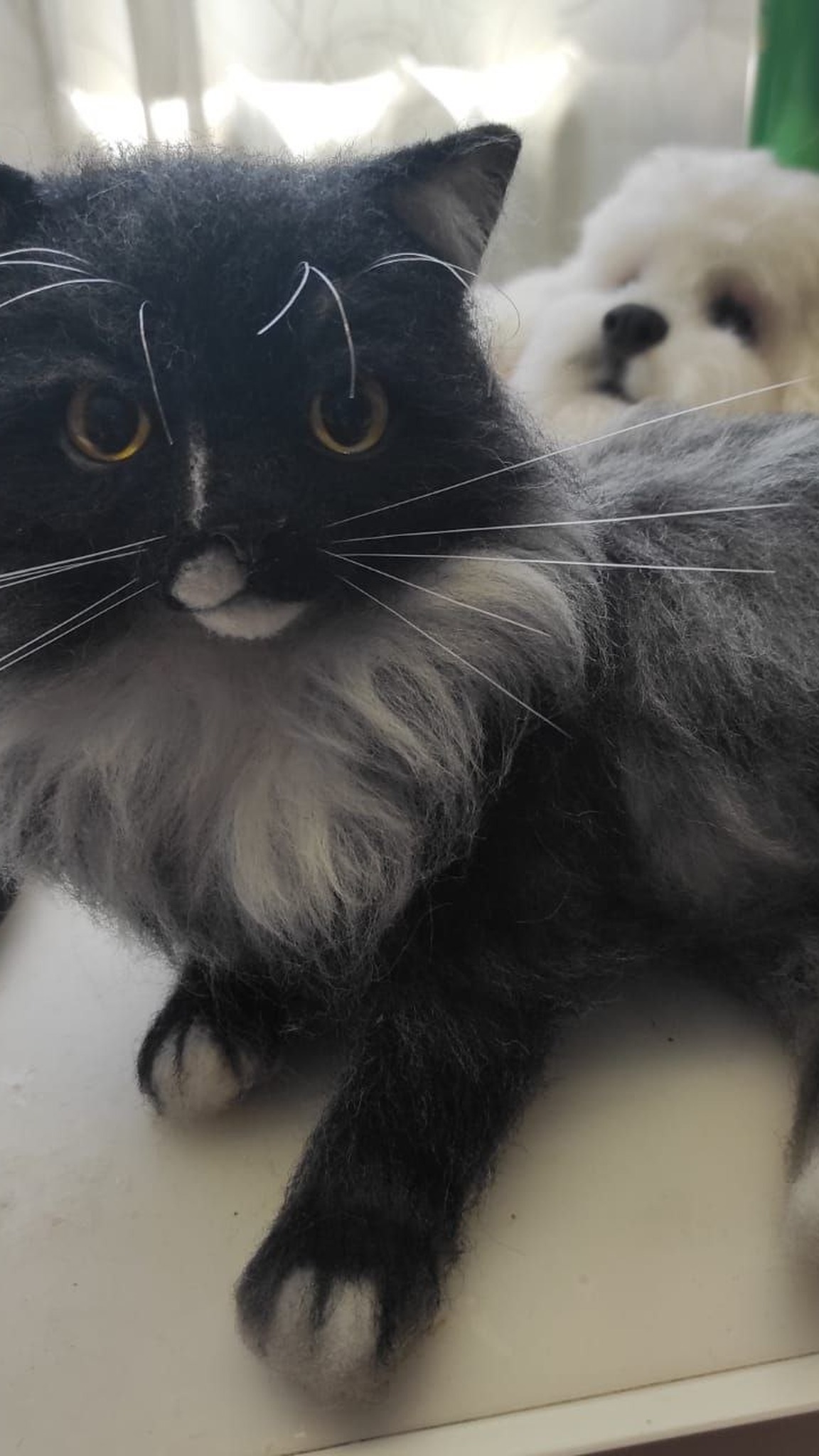 Realistic fluffy cat plush on the work table in our studio, white bib and amber eyes, made to order