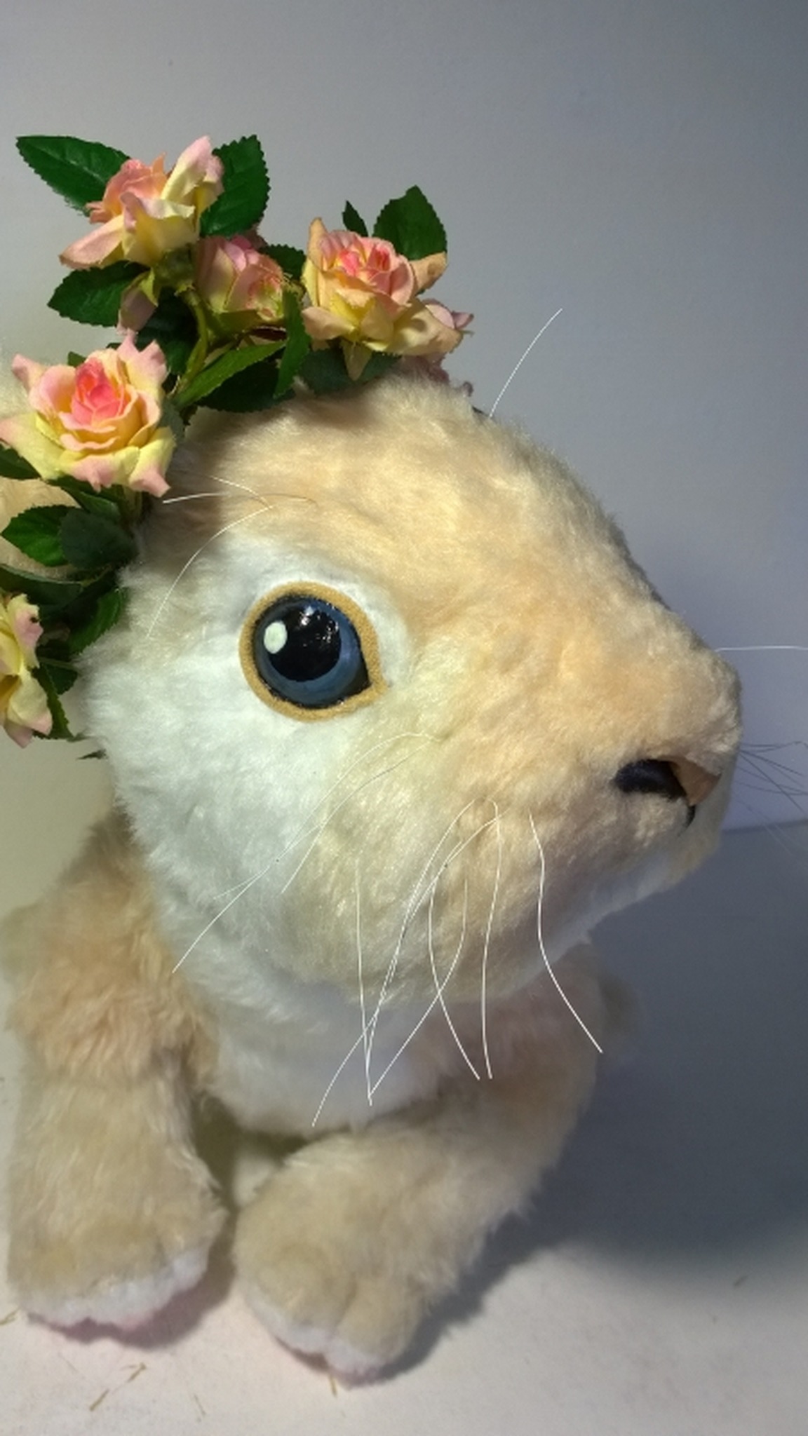 Realistic stuffed bunny with a white muzzle, long whiskers and pink roses on its head, custom made by hand