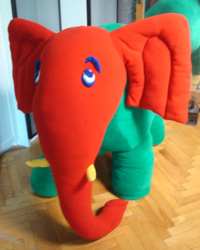 Red and green elephant plush with blue eyes Red and green elephant plush with blue appliqué eyes, raised brows and yellow tusks, custom made from kids' art