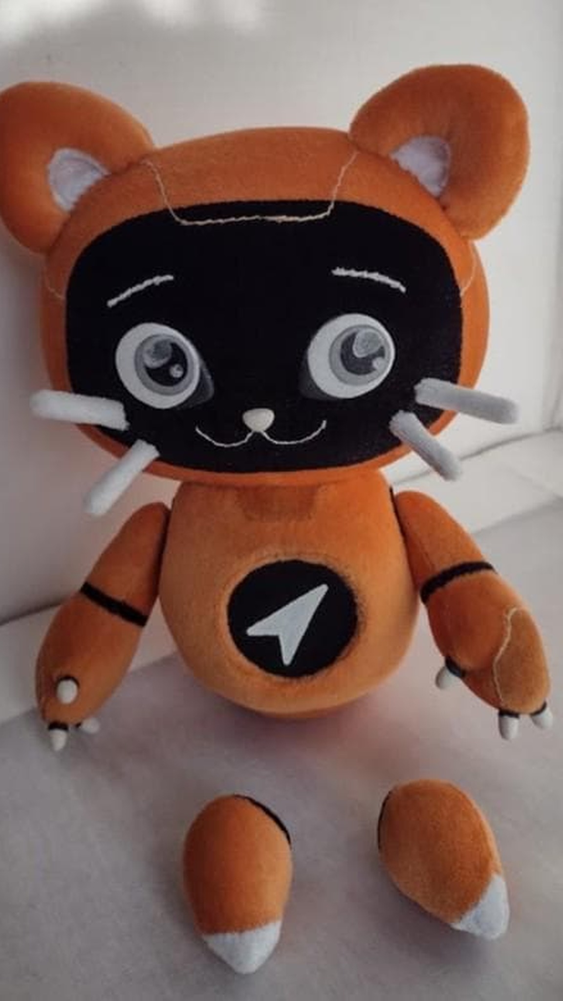 Orange robot cat mascot plush sitting with its magnetic legs off, custom logo on the chest, made to order