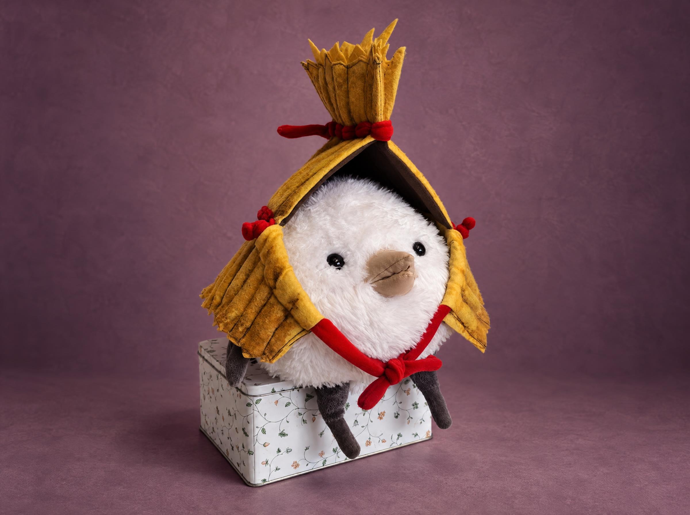 Round bird plush in a straw hat Round white bird plush in a straw cape tied with red cords, sitting on a floral tin, made to order