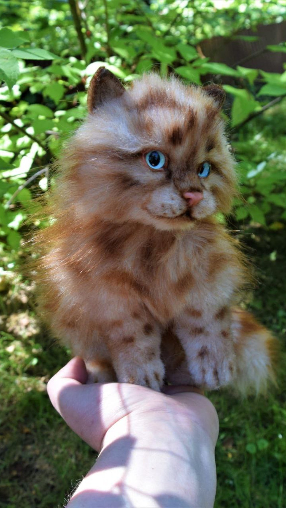 Small realistic kitten plush sitting on an open hand, ginger tabby faux fur, made to order
