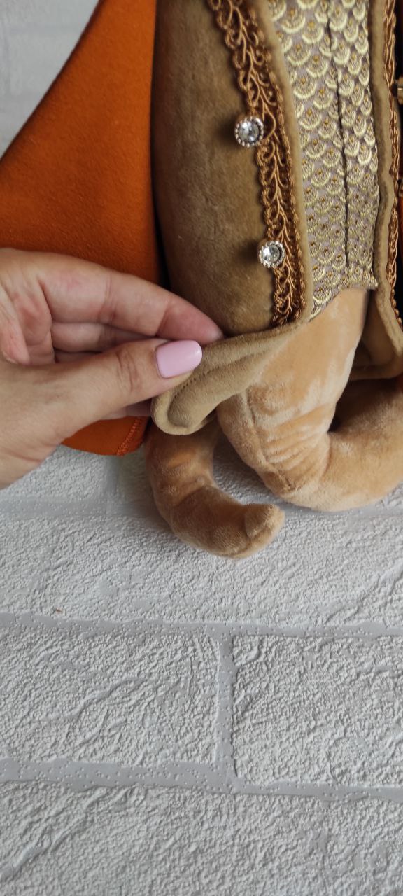 Snake plush tail under the cape Velvet cape lifted to show the curled tail of a handmade Year of the Snake plush, custom corporate order