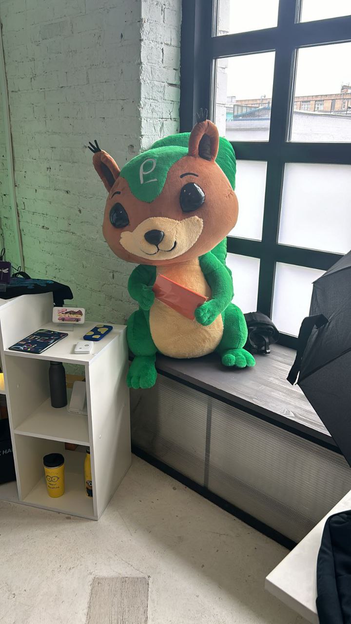 Squirrel mascot plush at the booth Squirrel mascot plush sitting on a windowsill at an exhibition booth, a big custom toy sewn to order