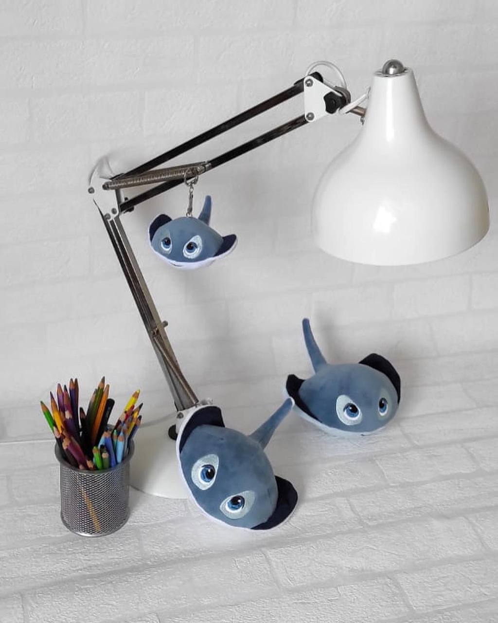 Stingray plush keychain on a desk lamp, made to order Stingray plush keychain hanging from a desk lamp, two more rays below, handmade corporate gift to order