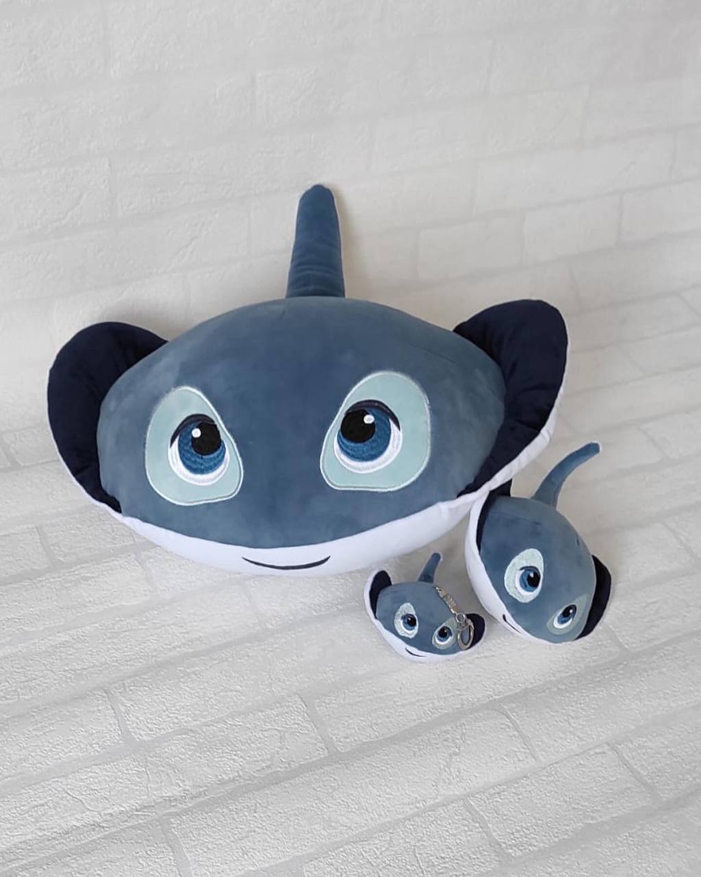 Stingray mascot plush pillow and keychains, made to order Big stingray plush pillow with embroidered blue eyes next to two small keychain rays, custom made to order