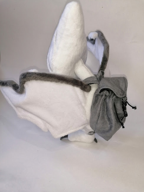 Tamagotchi plush wearing its backpack White pterodactyl tamagotchi plush wearing its grey backpack, a handmade lost-toy gift made to order