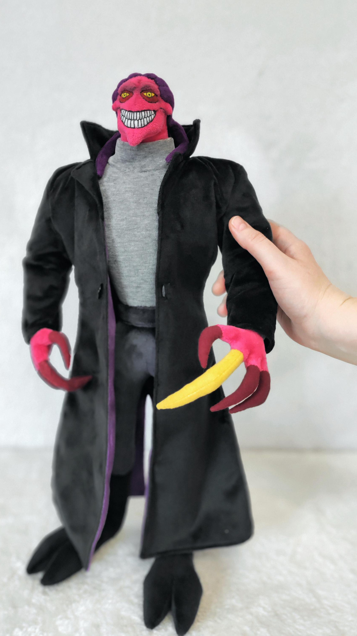 Thrax plush doll held by hand to show its 50 cm size, black coat and grey turtleneck, sewn to order
