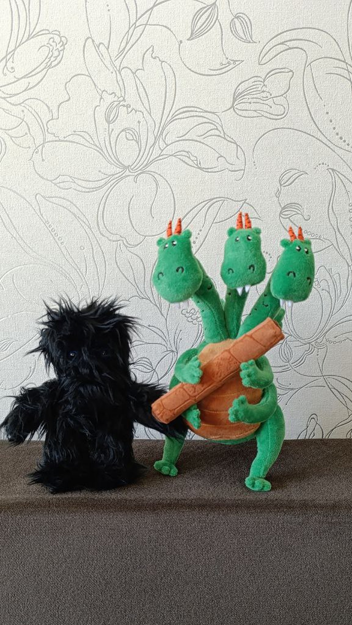 Three-headed dragon plush hugging a wafer roll beside a black shaggy plush, handmade dragon made to order
