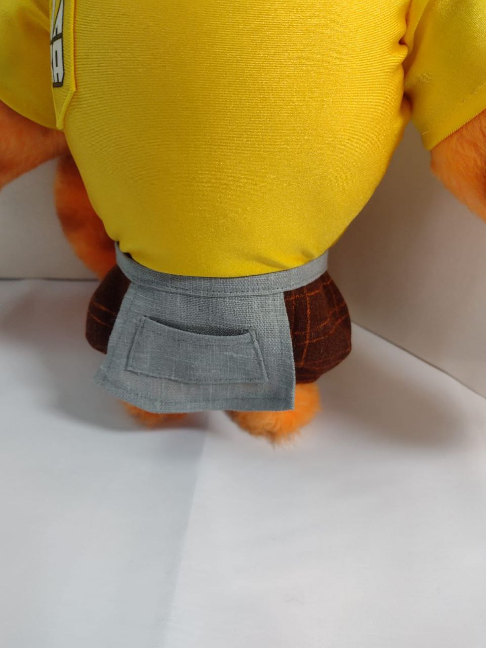 Tiger mascot plush apron and plaid shorts Tiger mascot plush grey apron with a pocket over brown plaid shorts and a yellow T-shirt, handmade to order