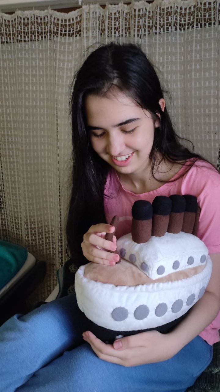 Girl hugging the Titanic-style plush pillow, a soft four-funnel ship sewn to order for hugging and sleep