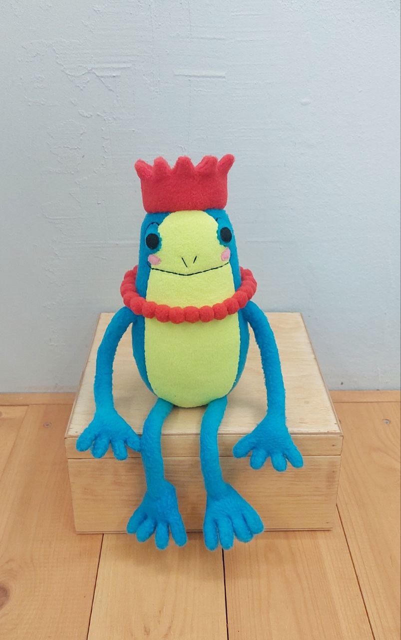 Turquoise frog plush in a crown Turquoise frog plush in a red crown sitting on a wooden box, long legs down, made to order from a sticker