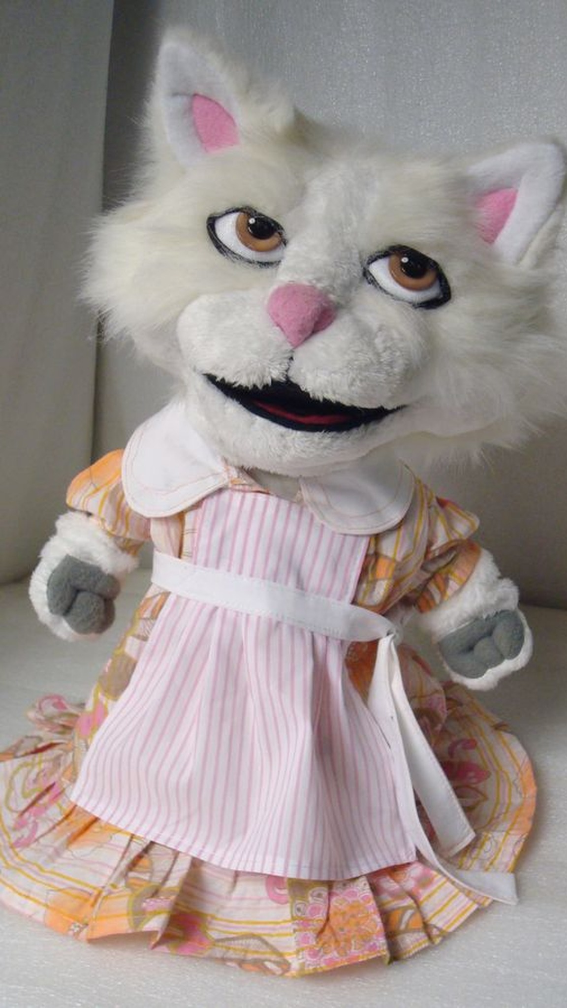 White cat hand puppet for TV in a floral dress and pink striped apron, custom puppet made to order