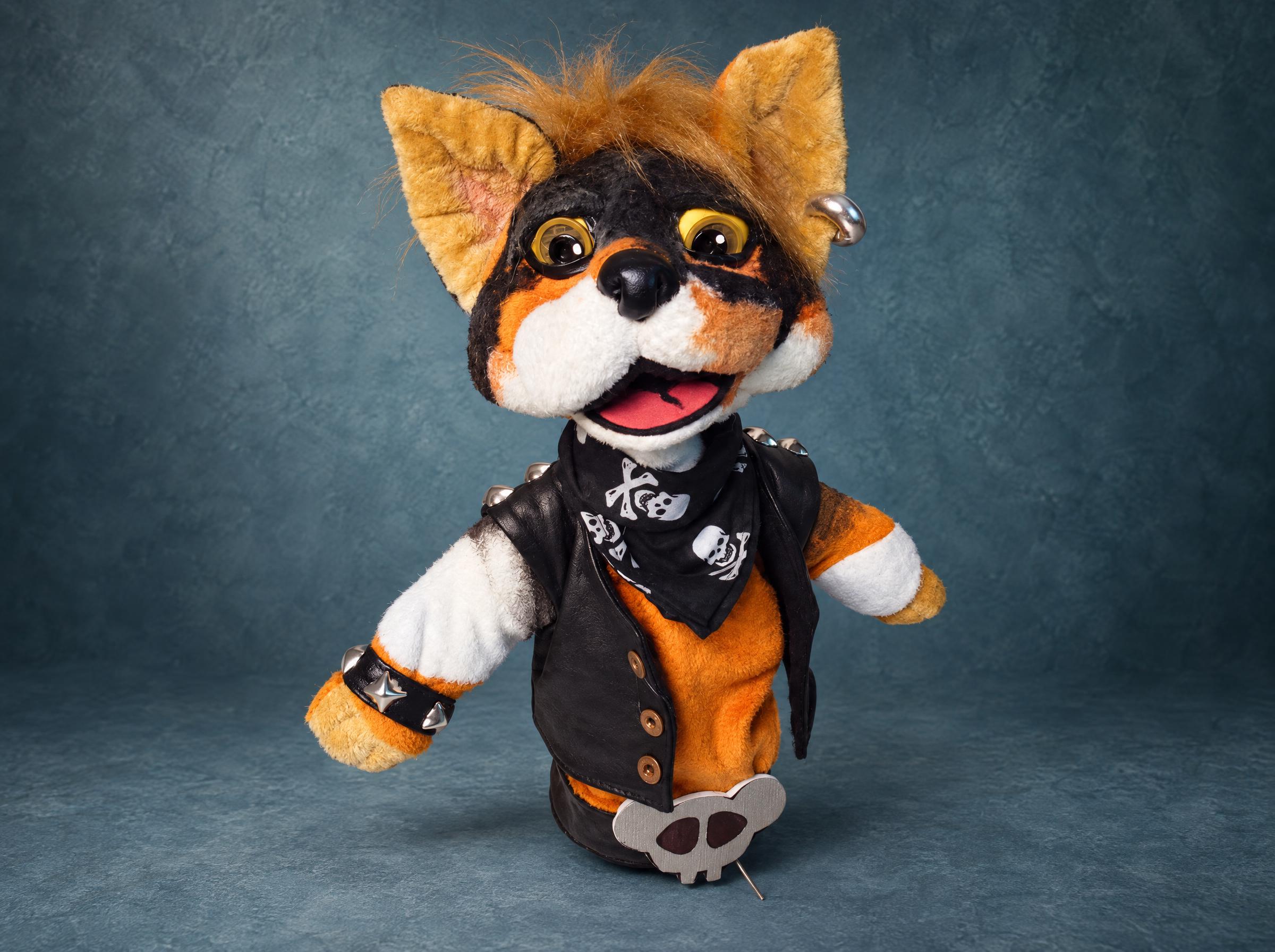Custom TV puppet of a punk cat in a studded faux leather vest and skull bandana, hand puppet made to order