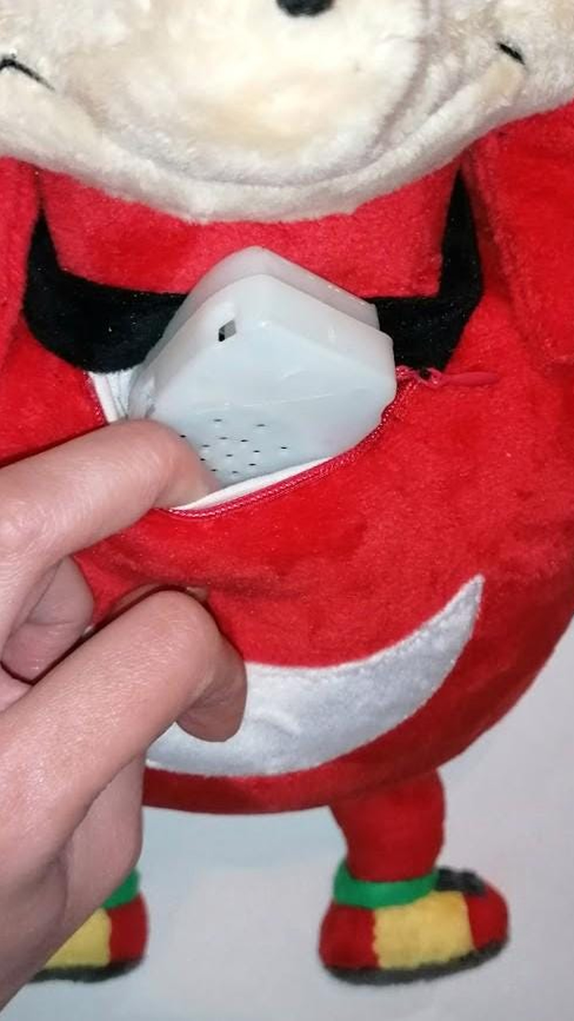 Voice module coming out of the zipped chest pocket of a Ugandan Knuckles talking plush made to order