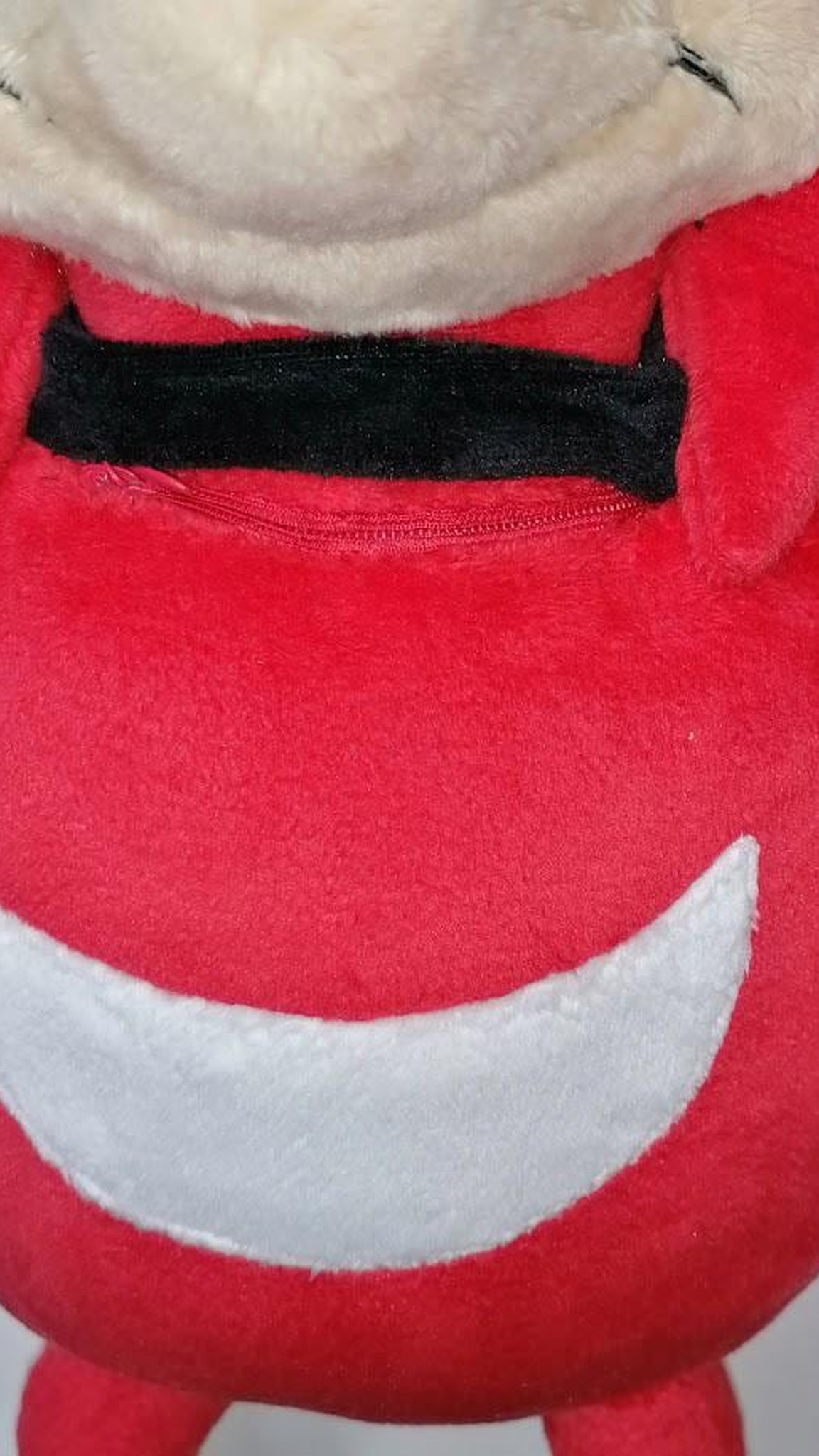 Hidden zip pocket under the black neck band of a custom Ugandan Knuckles talking plush, sewn by hand