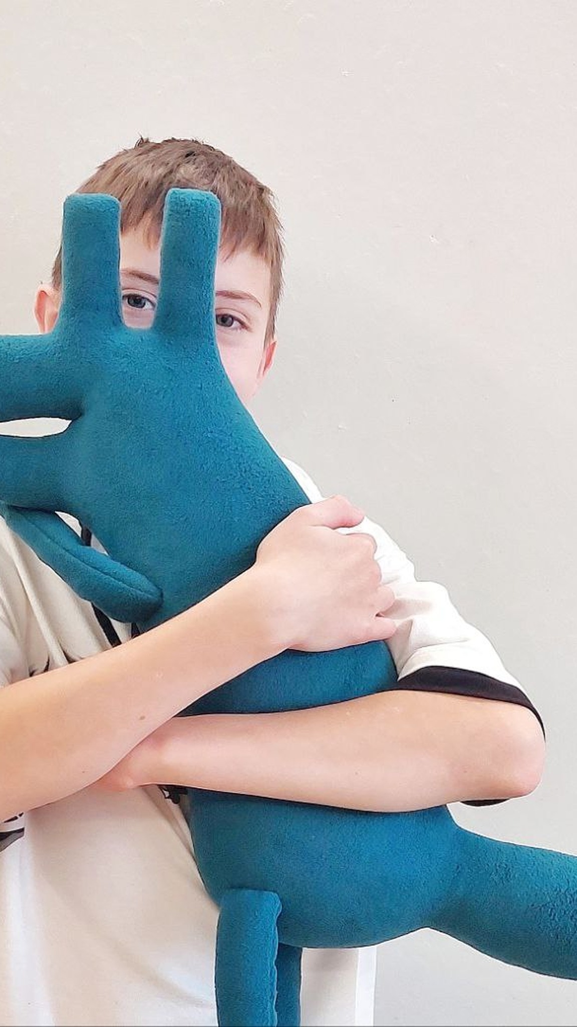Boy hugging the big teal vet clinic mascot plush dog with both arms, custom logo plush toy sewn by hand to order