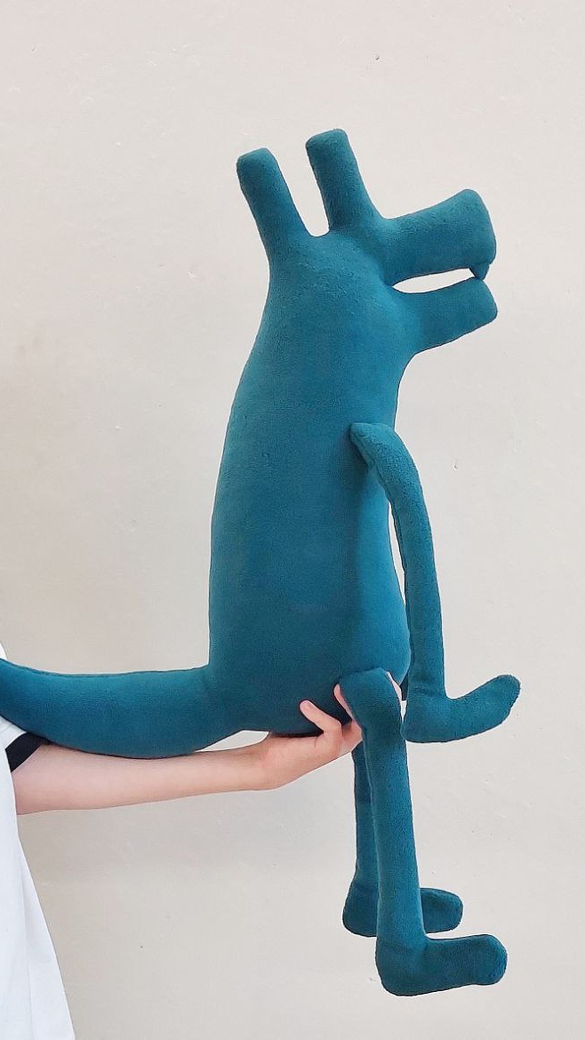 Boy holding the teal vet clinic mascot plush dog by its body, long legs dangling, logo plush toy made to order