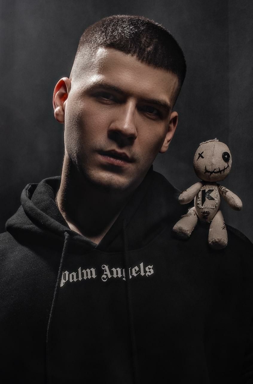 Voodoo doll merch on a performer shoulder Handmade voodoo doll with a K chest patch riding on a performer shoulder in a merch portrait, made to order