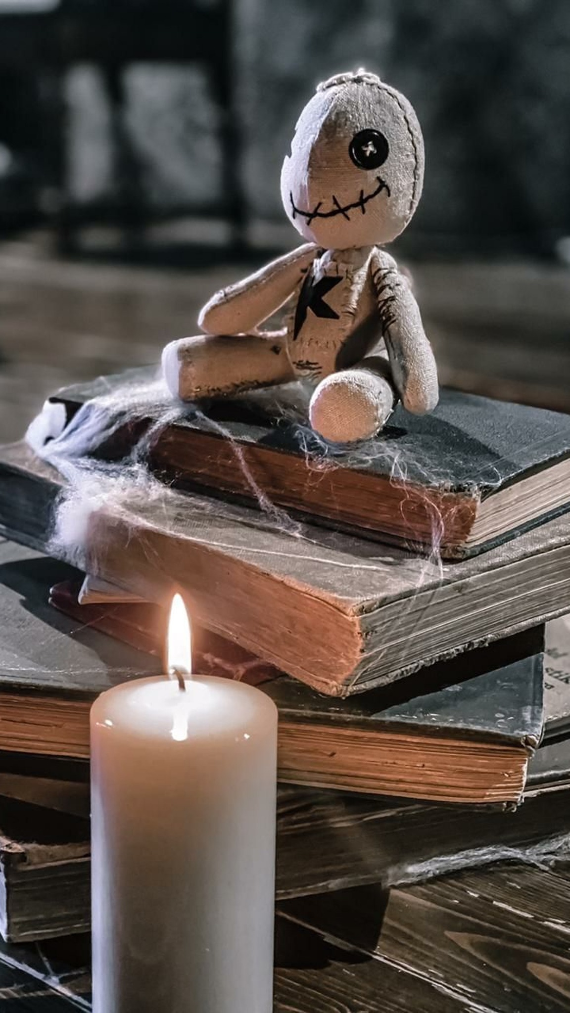 Voodoo doll plush merch on a stack of old books with cobwebs and a candle, handmade to order