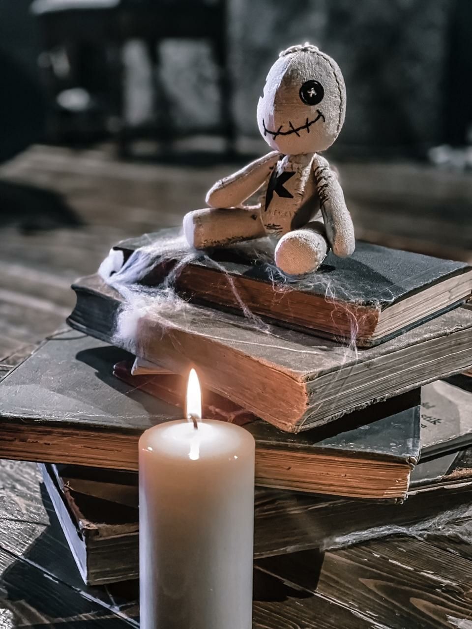 Voodoo doll merch in a photo shoot Custom voodoo doll merch sitting on old books by a candle in the artist photo shoot, sewn to order
