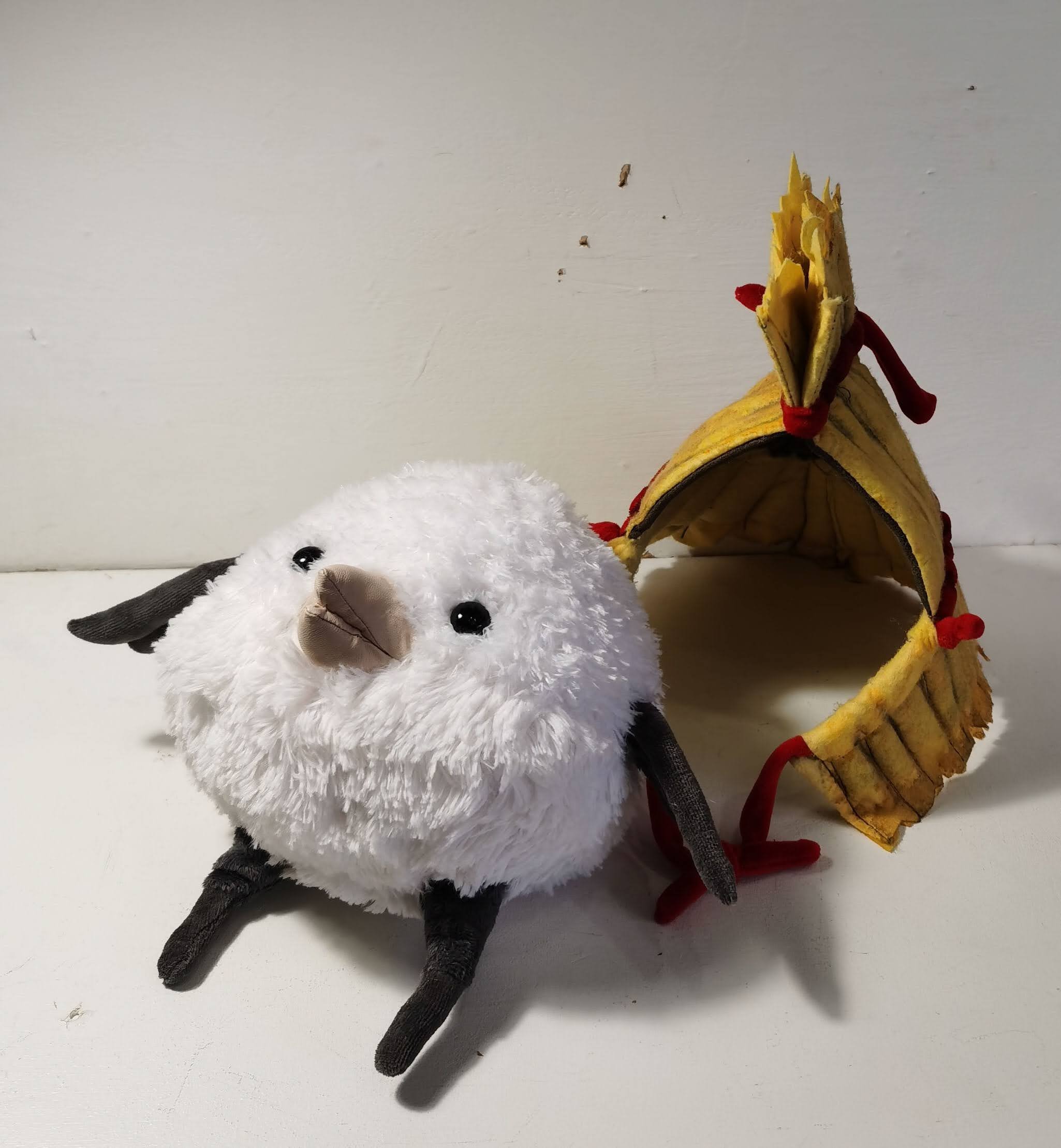 White bird plush with a removable straw cape White bird plush with grey wings and legs beside its removable straw cape with red ties, made to order