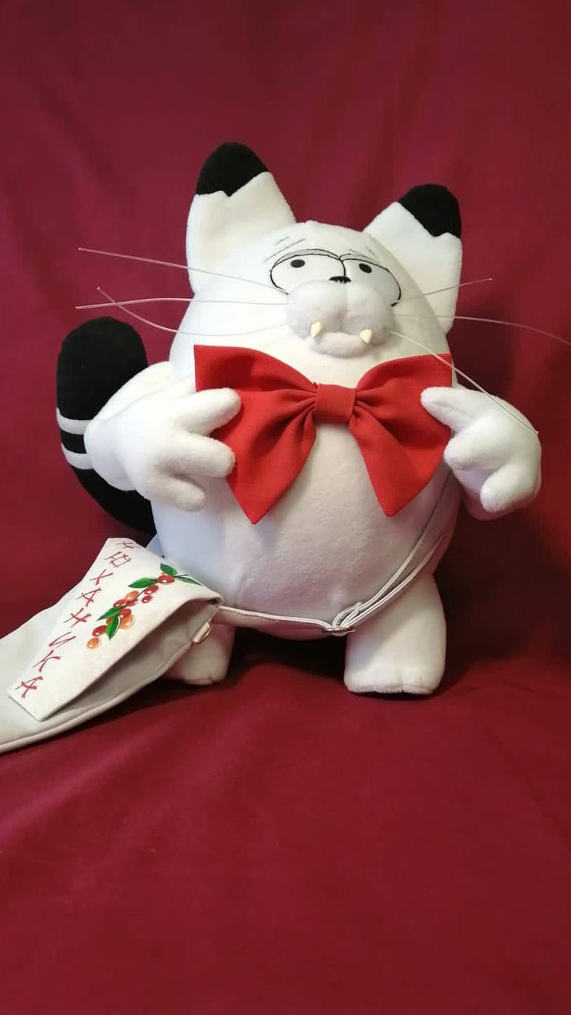 White cat plush Kokos with fangs and a red bow, black-tipped ears and a striped tail, sewn to order
